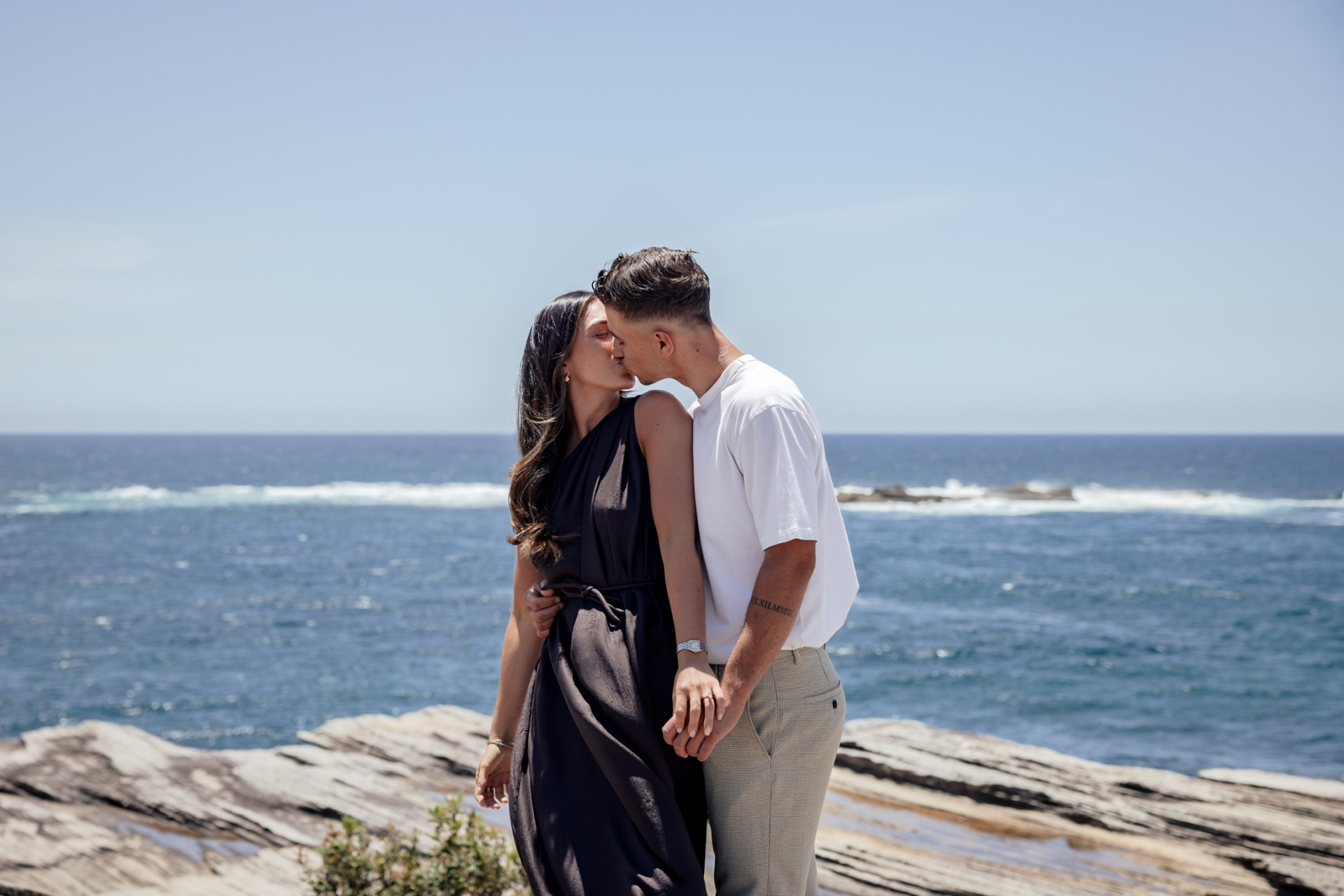 Isabella and David holding hands by the sea